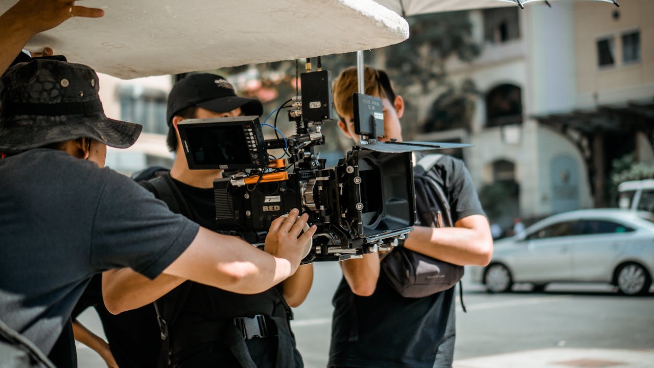 pexels-photo-3062541 A film crew operates a RED camera on a city street, capturing a professional scene.